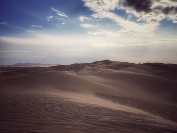 Scenic view of desert against cloudy sky