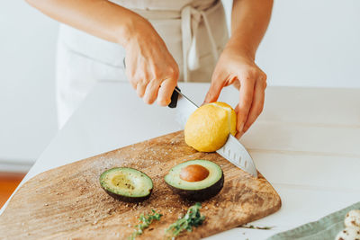 Female hands cutting lemon on a cutting board