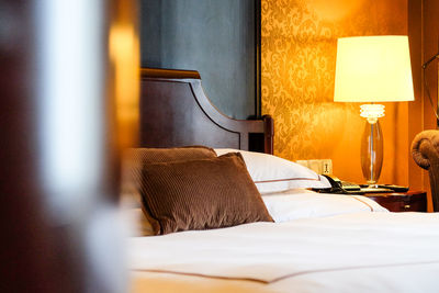 Pillows on bed in illuminated bedroom at home
