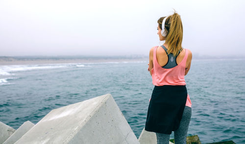 Rear view of woman standing by sea against sky