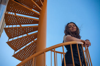 Low angle view of woman standing against blue sky