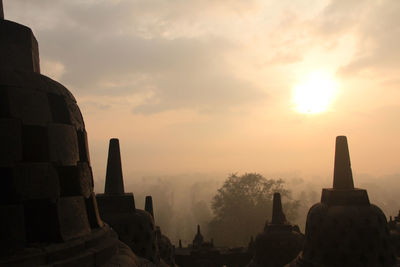 Silhouette of temple against cloudy sky