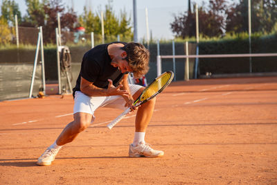 Full length of young man playing tennis on field