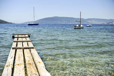 Sailboats moored on sea against clear sky