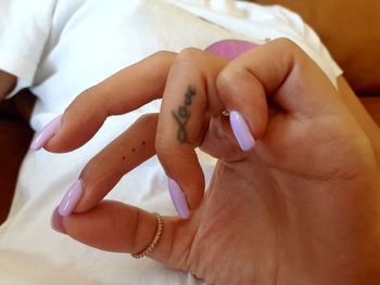 Midsection of woman showing love text tattoo on finger