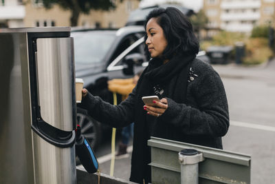 Side view of young woman using mobile phone in bus