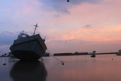 Fishing boat in sea against sky during sunset