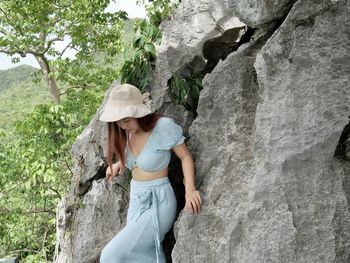 Portrait of young woman standing against rock