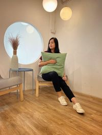 Portrait of woman sitting on wall at home