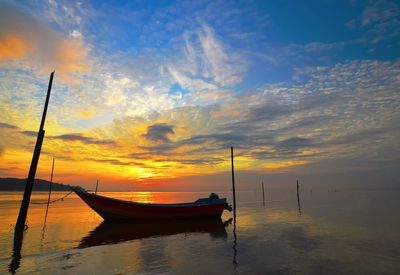 Sailboat moored on sea against sky during sunset