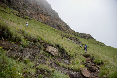 Hikers walking on mountain against sky