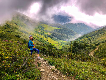 Young woman standing on mountain against sky