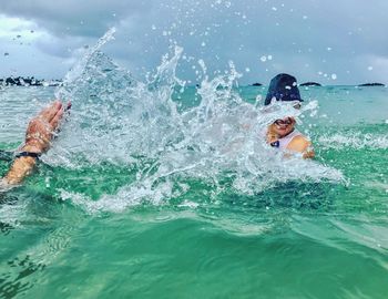 Friends splashing water while enjoying in sea