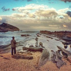 Man standing on beach against cloudy sky