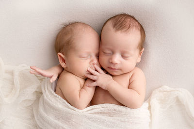 Cute twin babies lying on bed at home