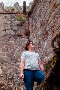 Low angle view of woman standing against stone wall