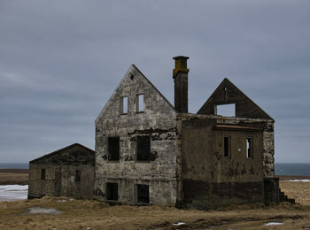 Abandoned building by sea against sky