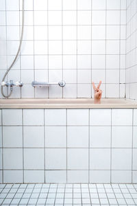 Cropped hand showing peace sign from bathtub