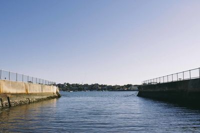 Bridge over river against clear blue sky