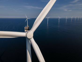 Low angle view of wind turbine in sea against sky