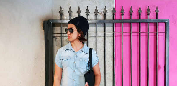 Woman wearing sunglasses standing against wall