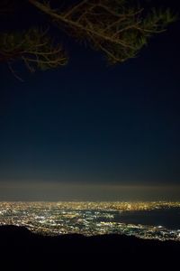 Illuminated cityscape by sea against sky at night