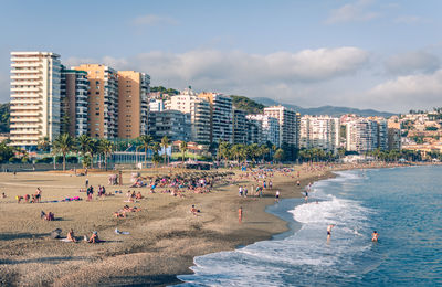 Group of people on beach against buildings in city