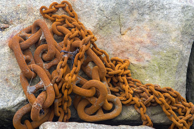 Close-up of rusty chain tied up on metal