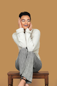 Portrait of young woman sitting against red background