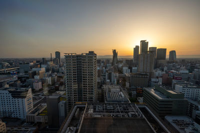 Aerial view of buildings in city against sky during sunset