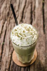 High angle view of milkshake with whipped cream in glass on table