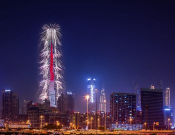 Firework display over illuminated buildings in city at night