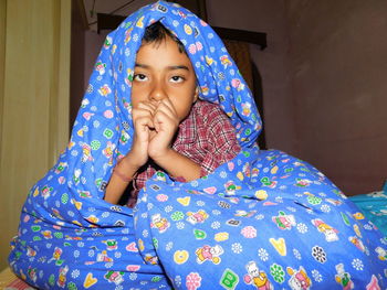Portrait of boy sitting with blanket at home