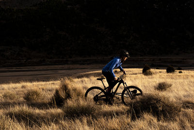 Woman silhouetted mountain biking during sunset