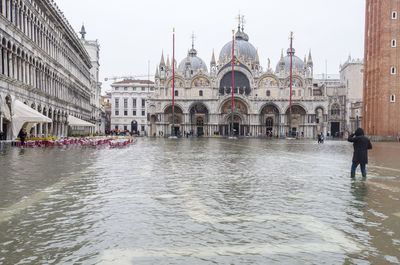 People by buildings in city during rainy season