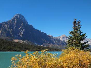 Scenic view of lake and mountains against clear blue sky