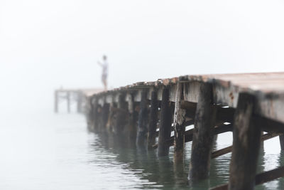 Faceless person standing on wooden pier near sea on playa de muro and enjoying misty morning