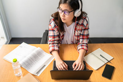 Young woman using mobile phone while sitting on table