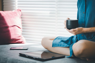 Midsection of woman holding coffee while sitting at home