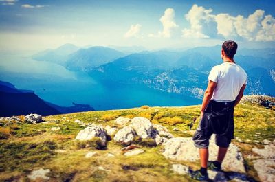 Rear view of man standing on mountain against sky