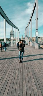 People on sidewalk in city against sky