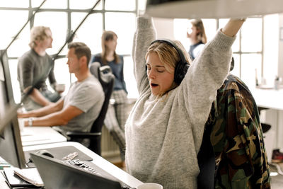 Female entrepreneur stretching while sitting at workplace