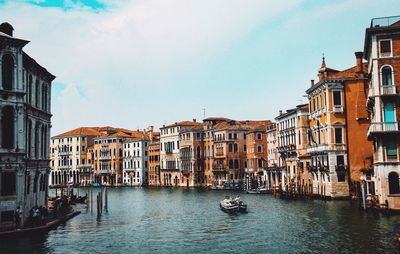 Canal in city against sky