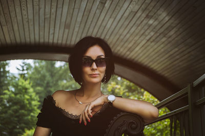 A pretty charming middle-aged woman in a black dress and sunglasses strolls through the city park