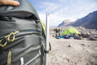 Detail of mountaineers ice axe strapped onto a backpack at campsite.