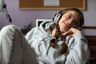 A happy girl in pigtails smiles while listening to music.