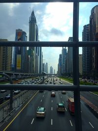 Cars on road amidst buildings in city against sky