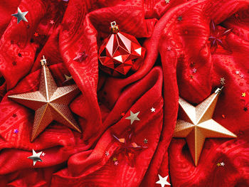 Bright red fabric with golden stars and ball. star confetti on folded textile background.