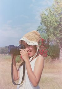 Portrait of woman holding camera on field