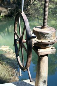 Close-up of rusty wheel by lake